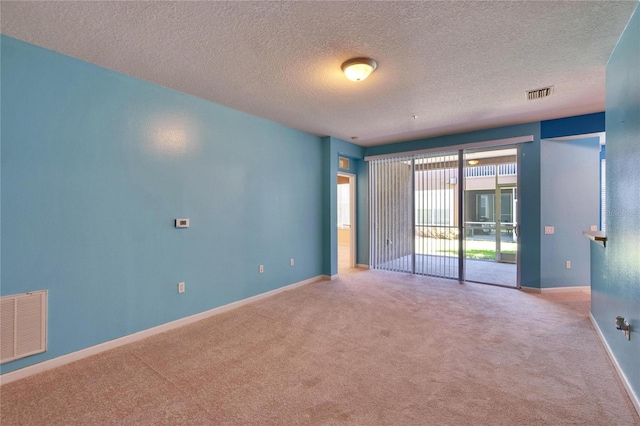 empty room with carpet, baseboards, visible vents, and a textured ceiling