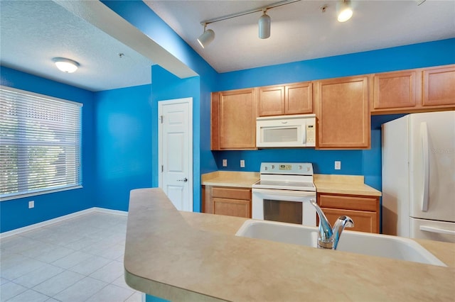 kitchen featuring a textured ceiling, white appliances, a sink, baseboards, and light countertops