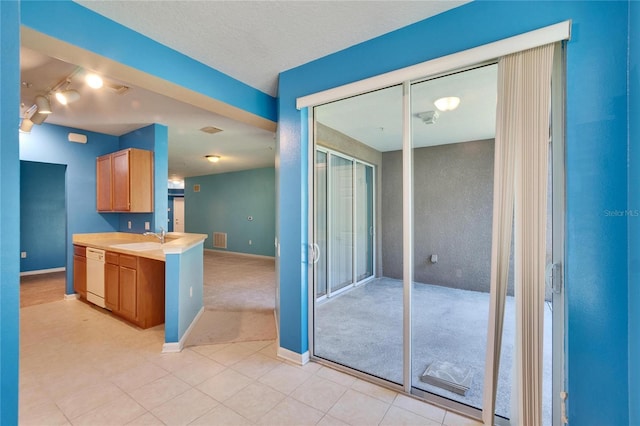 kitchen with a sink, baseboards, light countertops, and dishwasher