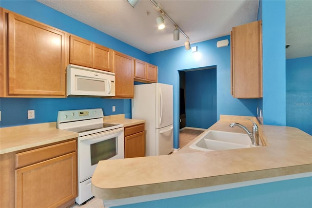 kitchen featuring light brown cabinets, a peninsula, white appliances, a sink, and light countertops