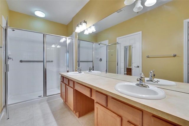 bathroom featuring double vanity, a stall shower, visible vents, tile patterned floors, and a sink