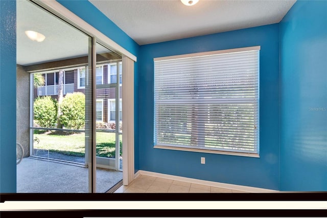 entryway with plenty of natural light, a textured ceiling, baseboards, and tile patterned floors