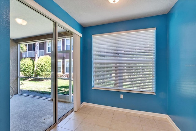 doorway to outside featuring plenty of natural light, a textured ceiling, and baseboards