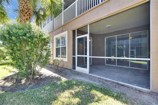 view of side of home featuring a sunroom and stucco siding