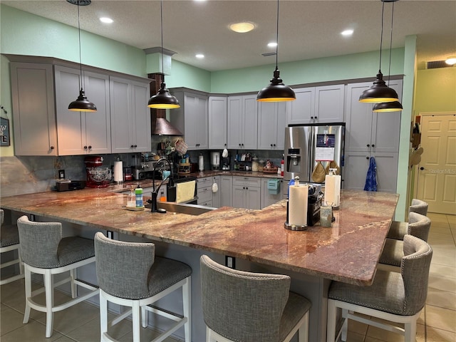 2069 Overbrook Ln, Spring Hill, FL 34606 - kitchen featuring stainless steel fridge, light tile patterned flooring, a sink, backsplash, and a kitchen breakfast bar