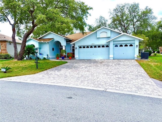2069 Overbrook Ln, Spring Hill, FL 34606 - ranch-style house featuring decorative driveway, an attached garage, a front lawn, and central air condition unit