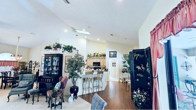 living area featuring lofted ceiling, an inviting chandelier, and wood finished floors