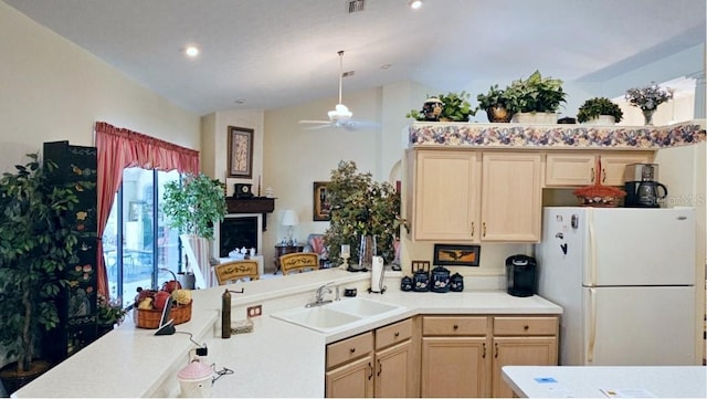 kitchen with light countertops, vaulted ceiling, a peninsula, freestanding refrigerator, and a sink