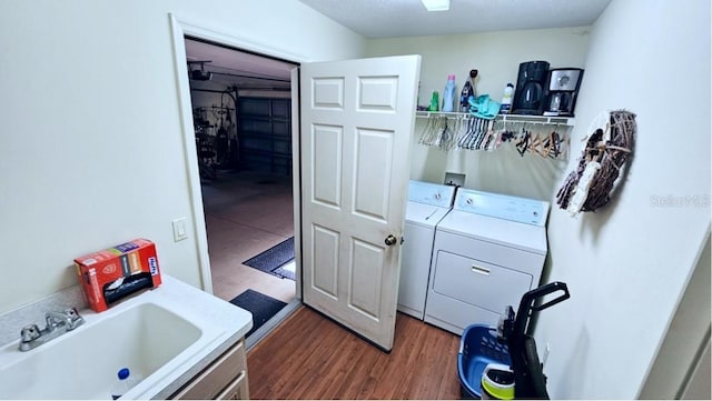 laundry room featuring laundry area, wood finished floors, separate washer and dryer, and a sink