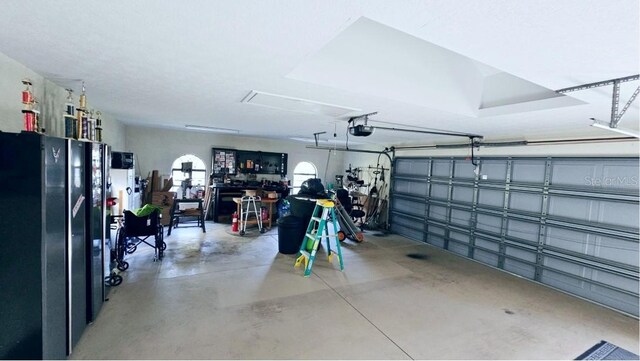 garage featuring a garage door opener and freestanding refrigerator