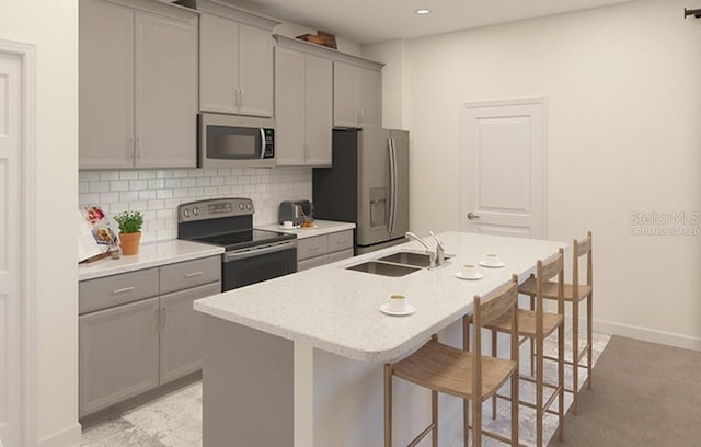 kitchen featuring decorative backsplash, appliances with stainless steel finishes, a breakfast bar, gray cabinets, and a sink