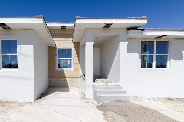 doorway to property featuring stucco siding