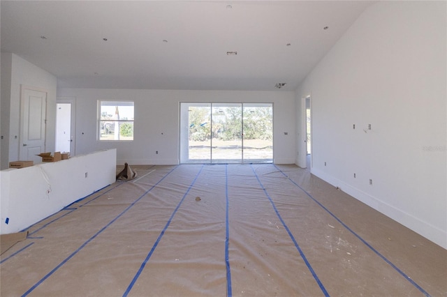 interior space featuring a towering ceiling, baseboards, and a wealth of natural light