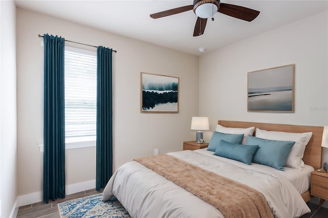 bedroom with a ceiling fan, multiple windows, baseboards, and wood finished floors