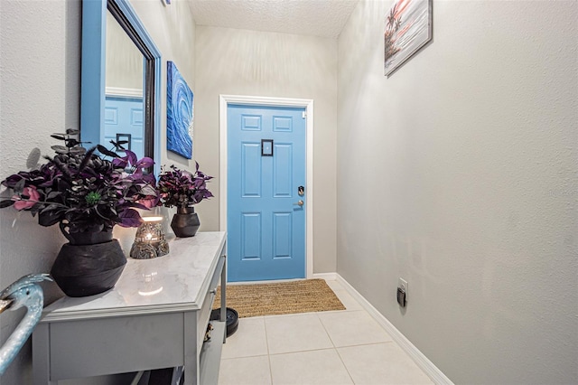 entrance foyer featuring a textured ceiling, light tile patterned flooring, and baseboards