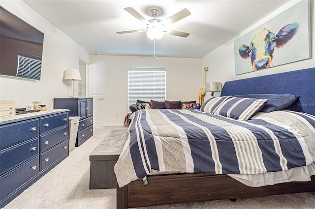 bedroom with ceiling fan, a textured ceiling, and light colored carpet