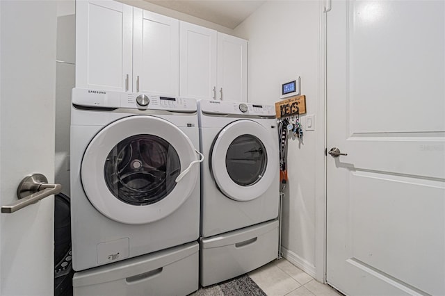 washroom with cabinet space, washer and dryer, and light tile patterned flooring