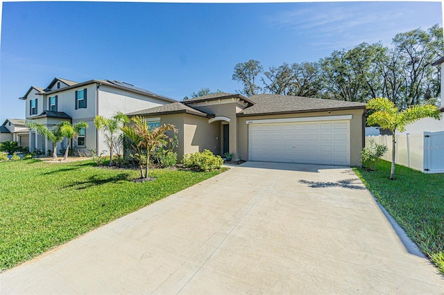 view of front facade with stucco siding, concrete driveway, a front yard, fence, and a garage