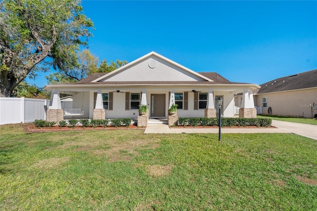 view of front of home featuring covered porch, ceiling fan, fence, and a front lawn