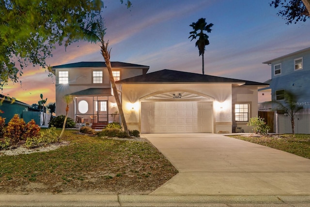 view of front facade with a garage, driveway, fence, and stucco siding