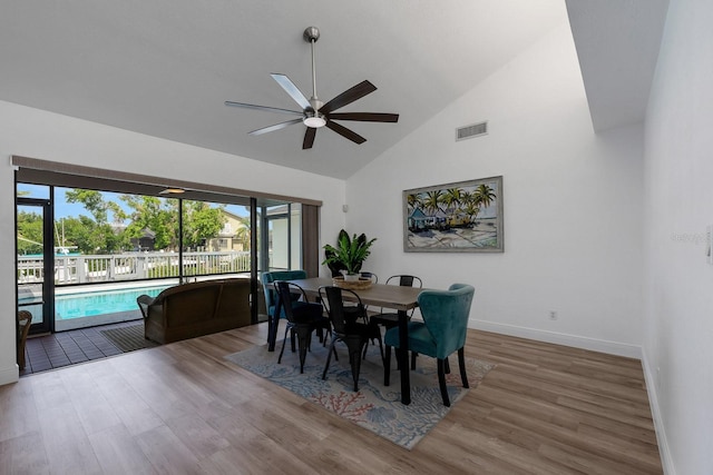 dining space with visible vents, a ceiling fan, wood finished floors, high vaulted ceiling, and baseboards