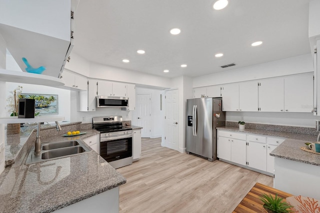 kitchen featuring light wood finished floors, appliances with stainless steel finishes, a sink, and visible vents