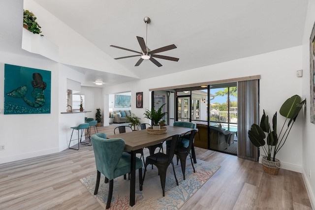 dining room with lofted ceiling, baseboards, ceiling fan, and light wood finished floors