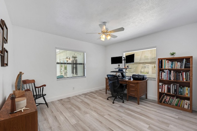 office area with baseboards, a healthy amount of sunlight, light wood-style flooring, and a textured ceiling