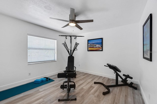 workout room with a textured ceiling, wood finished floors, a ceiling fan, and baseboards