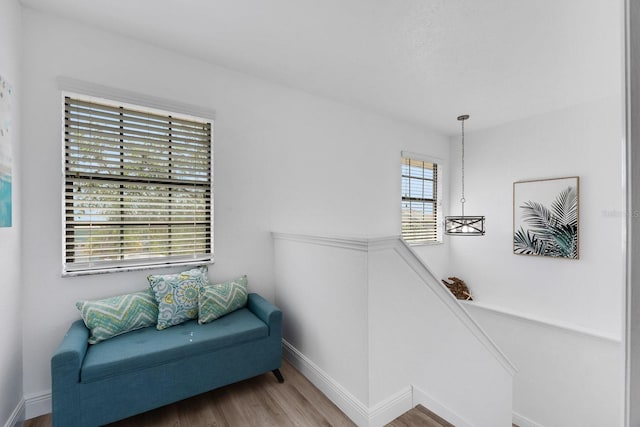 sitting room featuring wood finished floors, an upstairs landing, and baseboards