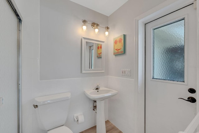 bathroom featuring wainscoting, tile walls, and toilet