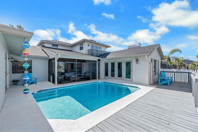 exterior space with a sunroom, a wooden deck, a fenced in pool, and stucco siding