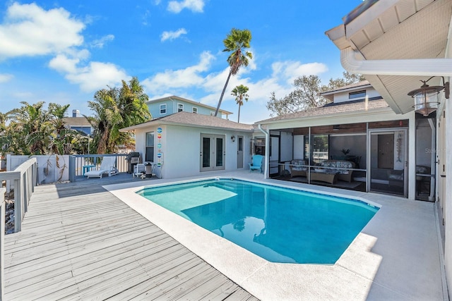 view of swimming pool with a fenced in pool, an outbuilding, french doors, a sunroom, and a deck