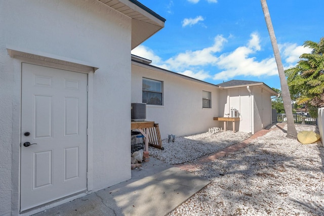 exterior space featuring central AC unit, fence, and stucco siding