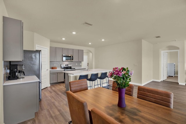 dining area featuring arched walkways, visible vents, and wood finished floors