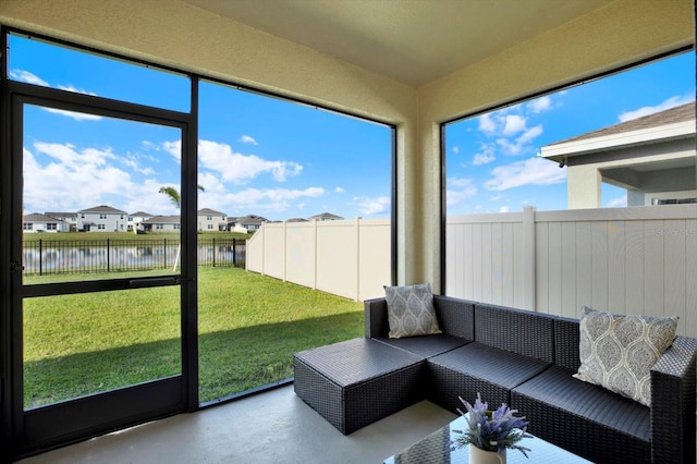 sunroom with a residential view and a water view