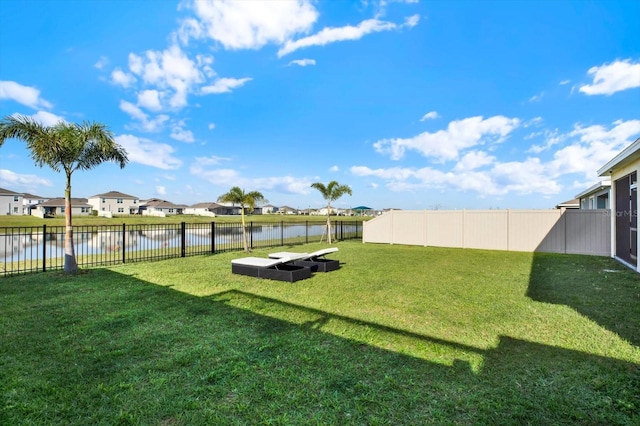 view of yard featuring a residential view, a fenced backyard, and a water view