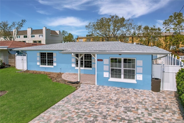 view of front of house featuring a shingled roof, fence, a gate, stucco siding, and a front yard