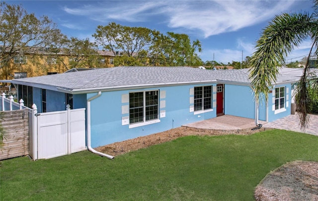 view of front of home featuring fence, a front lawn, and stucco siding