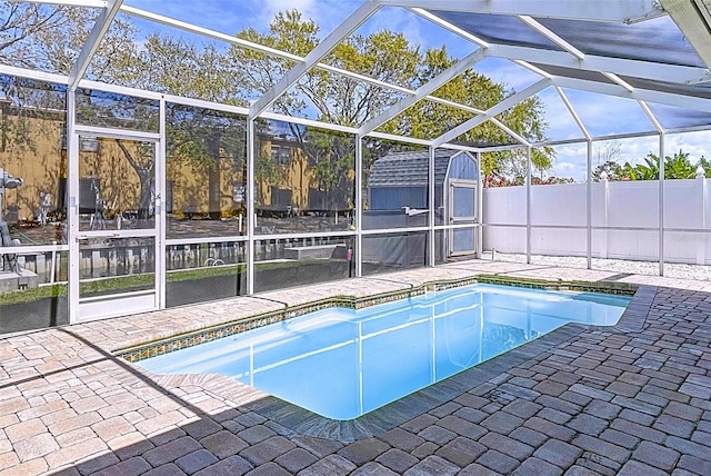 view of swimming pool with a storage shed, a patio, an outbuilding, and glass enclosure