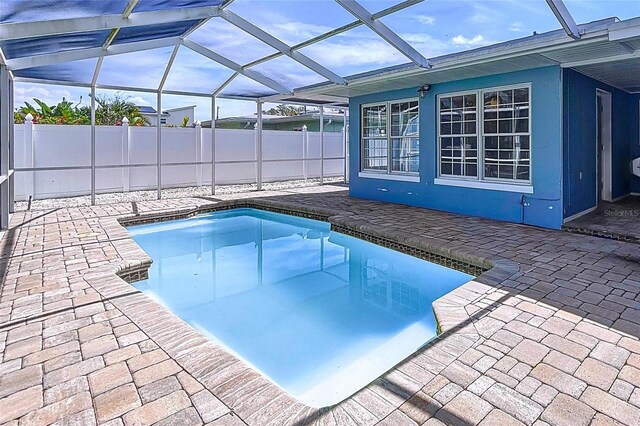 view of swimming pool featuring a patio, glass enclosure, fence, and a fenced in pool