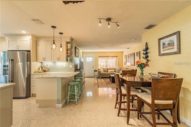 kitchen featuring visible vents, light countertops, open shelves, tasteful backsplash, and stainless steel fridge