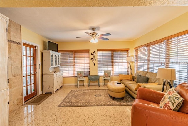 living area with ceiling fan, baseboards, and speckled floor