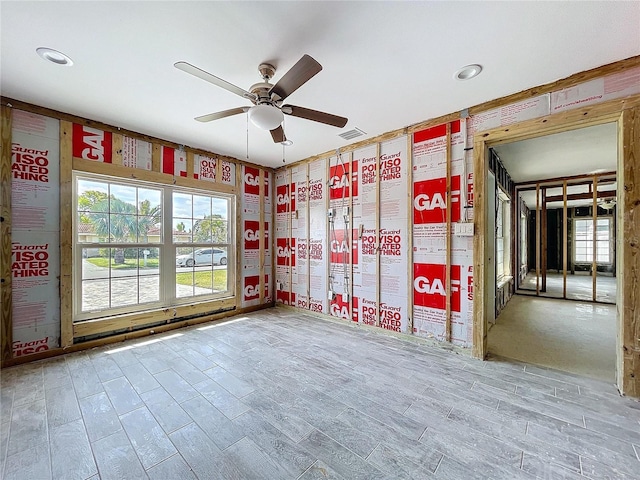 spare room with a ceiling fan, a wealth of natural light, visible vents, and wood finished floors