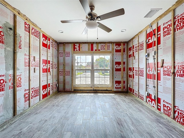 interior space with a ceiling fan, visible vents, and wood finished floors