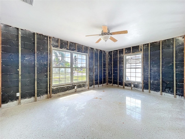 empty room featuring visible vents, a ceiling fan, and speckled floor