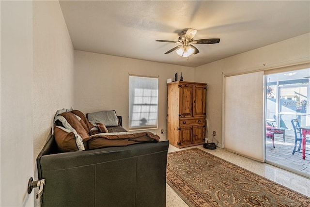 living area with speckled floor and a ceiling fan