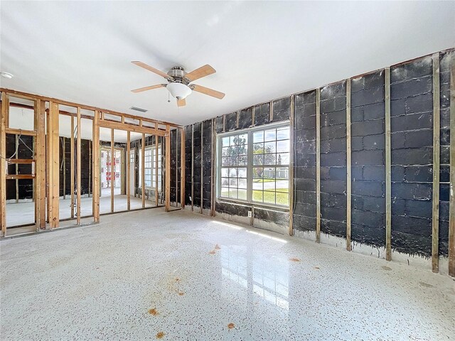 unfurnished room with ceiling fan, speckled floor, and visible vents