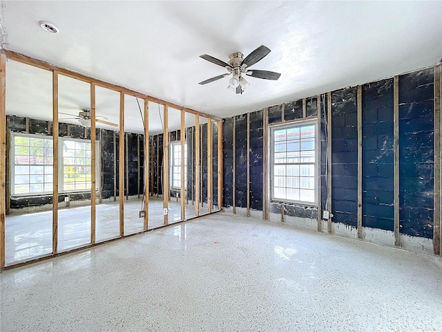 empty room with a ceiling fan and speckled floor