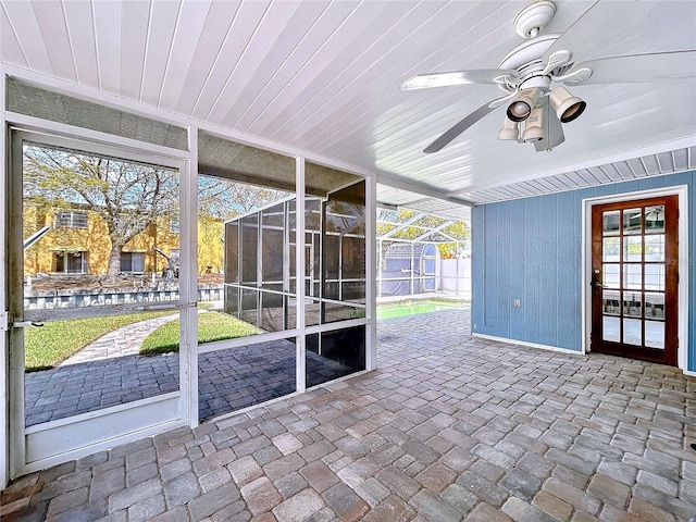 unfurnished sunroom with wooden ceiling, a wealth of natural light, and a ceiling fan